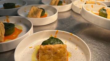 Una serie de platos blancos con comida, dispuestos sobre una encimera de acero inoxidable.