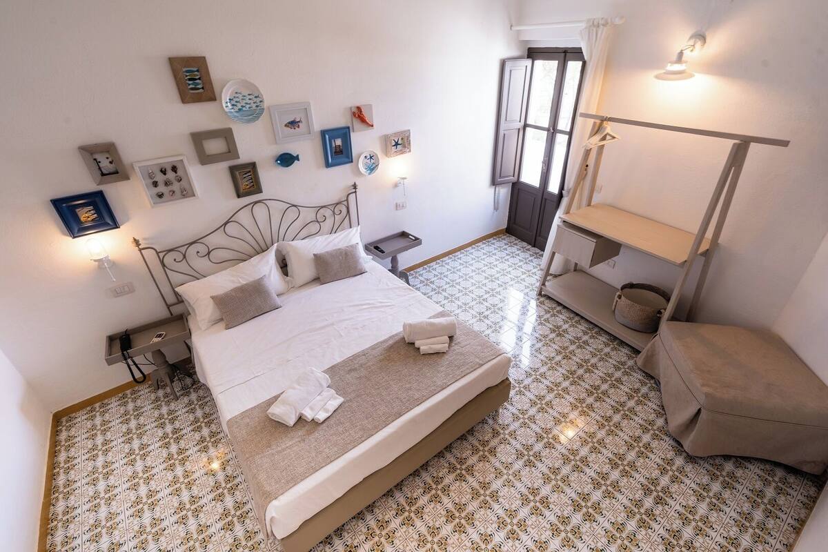 A neatly arranged bedroom with a bed, bedside tables, a hanging light, and a wardrobe.
