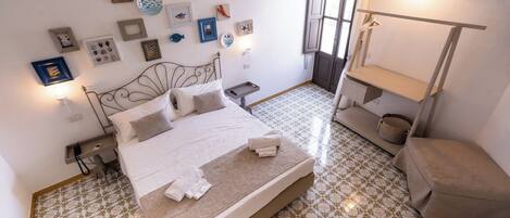 A neatly arranged bedroom with a bed, bedside tables, a hanging light, and a wardrobe.