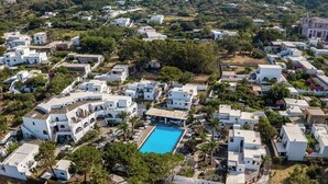 An aerial view of a coastal village with white buildings, a central swimming pool, and a mountain in the background. - La Sciara Resort Hotel (Lipari)
