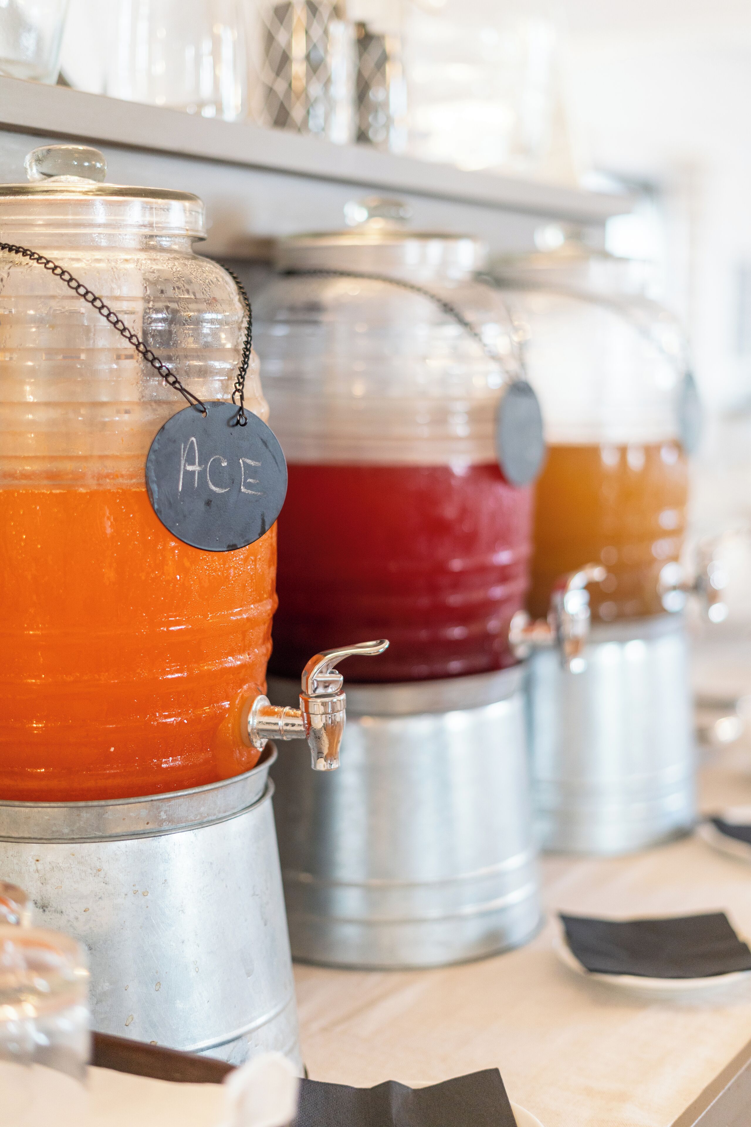 A row of beverage dispensers with labels, including one labeled "ACE".