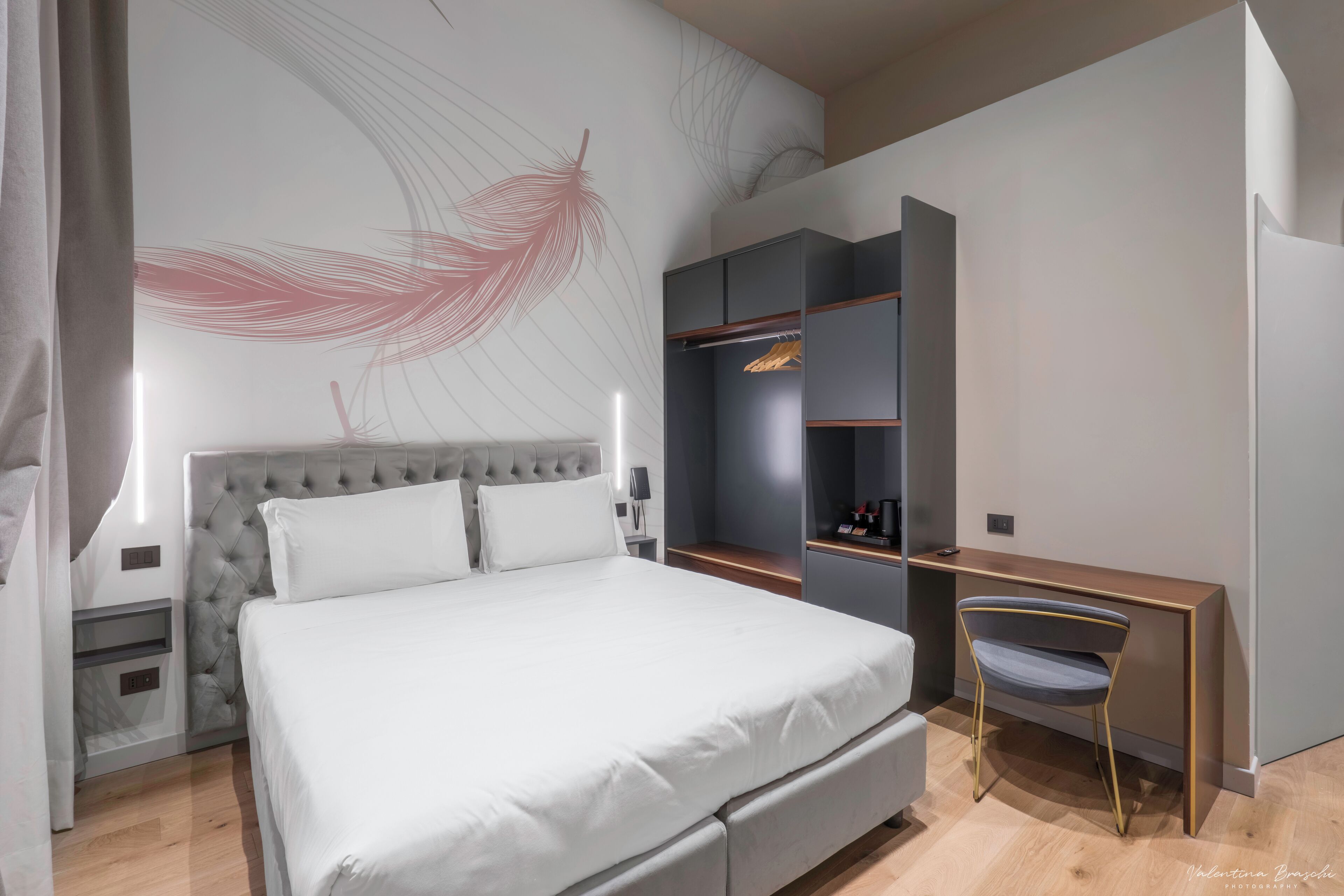 A modern bedroom with a large bed, a wardrobe, and a desk.