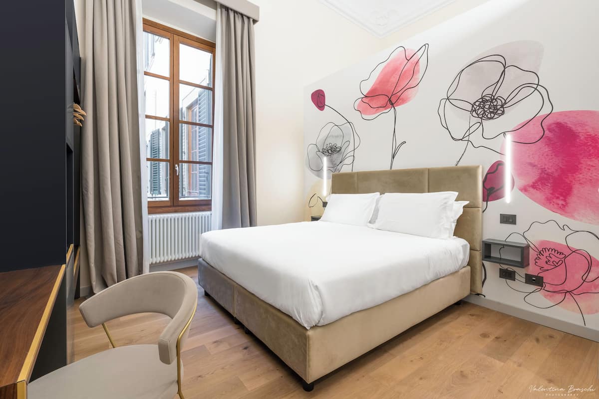 Ein Schlafzimmer mit einem großen Bett, einem Sessel und einem Fenster mit Vorhängen.