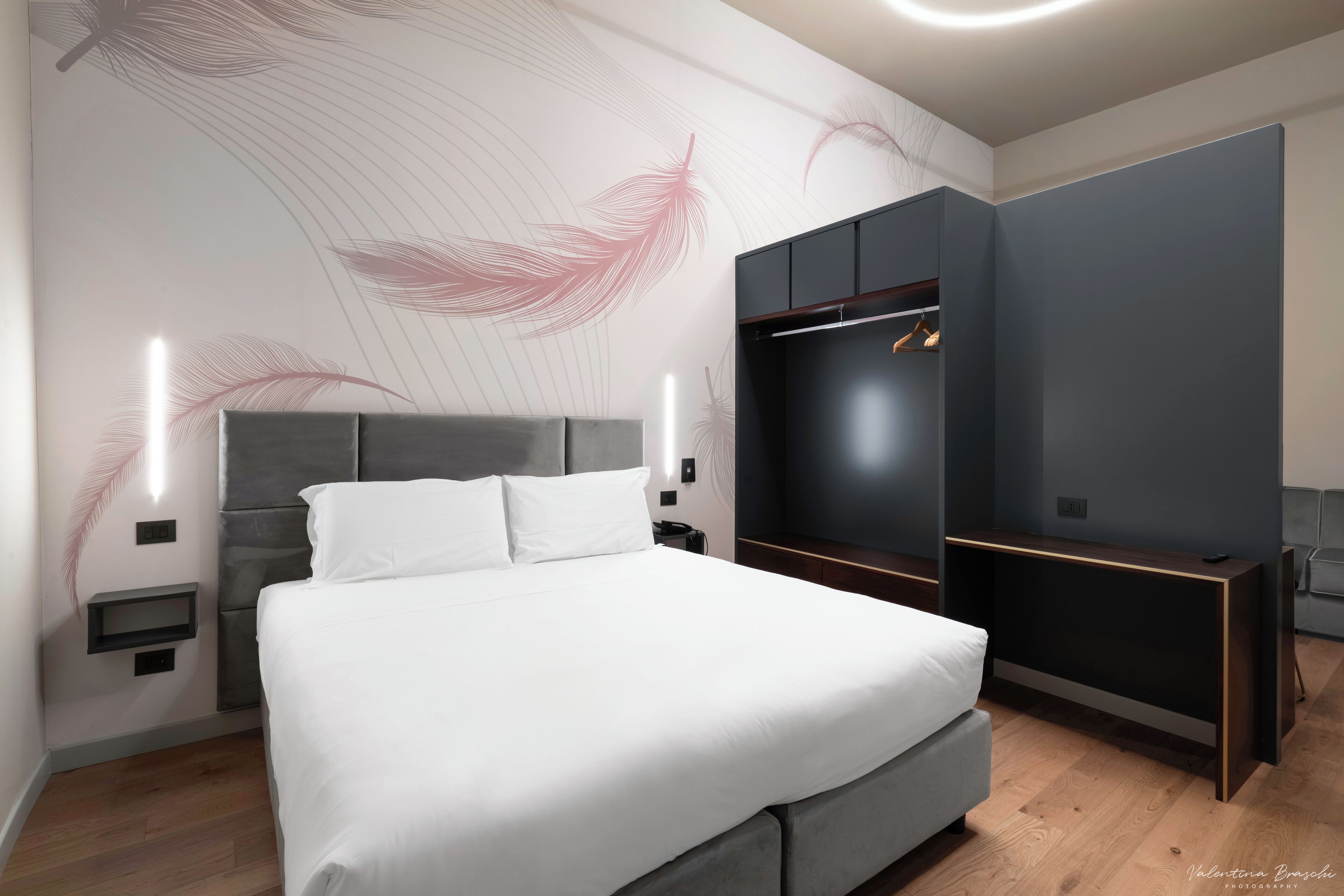 A modern bedroom with a large bed, built-in wardrobe, and decorative wall art.
