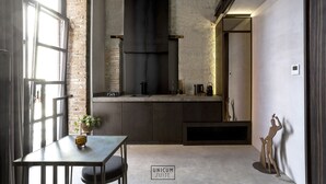 A modern kitchen with a brick wall, a large window, and a dining area with a table and chairs. - Unicum Suite Napoli Centro Storico (Naples)