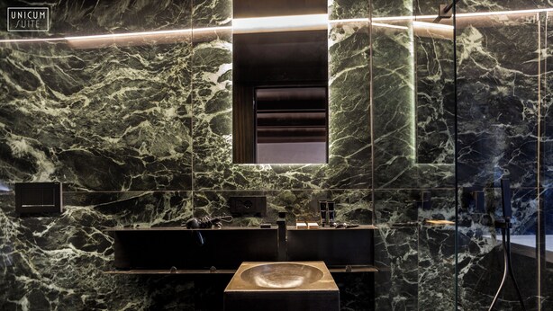 A modern bathroom with a marble wall, a large sink, and a mirror. - Unicum Suite Napoli Centro Storico (Naples)