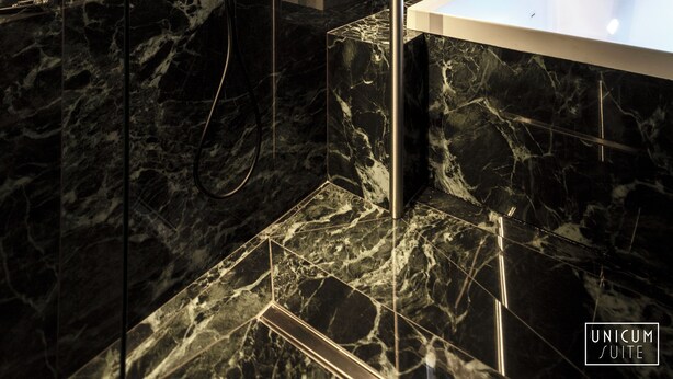 A modern bathroom with a marble wall, a freestanding bathtub, and a showerhead. - Unicum Suite Napoli Centro Storico (Naples)