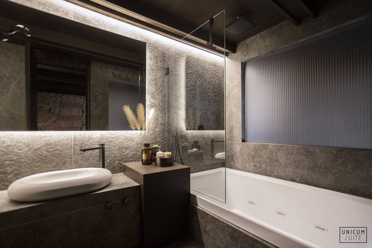 A modern bathroom with a large mirror, a bathtub, and a sink.