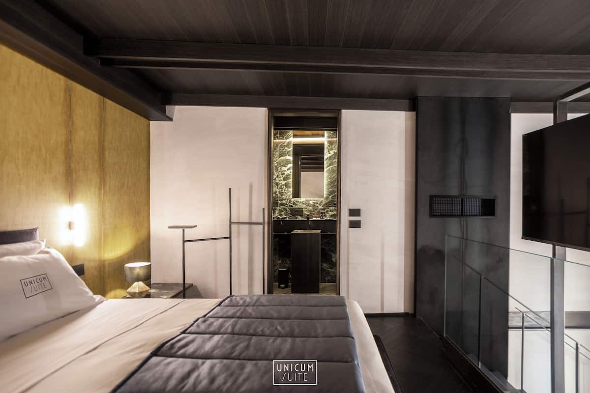 A modern hotel room with a bed, bedside table, and a view of the interior.
