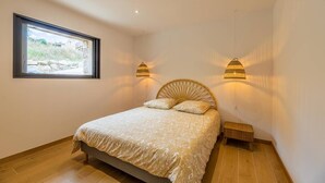 A bedroom with a bed, a window, and two wall-mounted lamps.