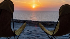 Two chairs facing a sunset over the ocean.