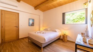 A bedroom with a wooden ceiling, a bed with white linens, a bedside table with a lamp, and a window with a view of greenery. - Bergerie mountain view heated swimming pool (SOTTA)