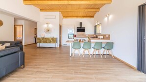 A modern living room with a wooden ceiling, a dining area with four chairs, and a kitchen with a stove and microwave. - Bergerie mountain view heated swimming pool (SOTTA)