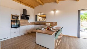 A modern kitchen with white cabinets, a wooden island, and a built-in oven. - Bergerie mountain view heated swimming pool (SOTTA)