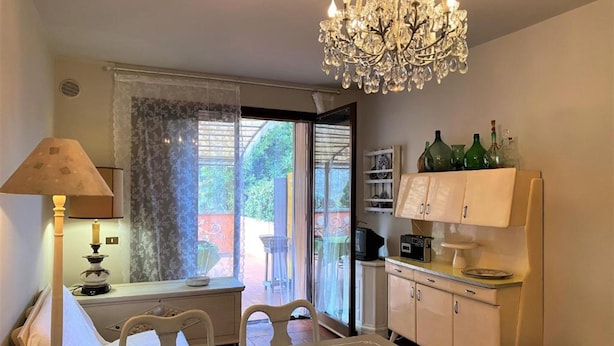 Un coin repas agrémenté d’un lustre, d’une table, de chaises, d’une lampe et offrant une vue par une fenêtre.