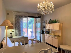 Un coin repas agrémenté d’un lustre, d’une table, de chaises, d’une lampe et offrant une vue par une fenêtre.