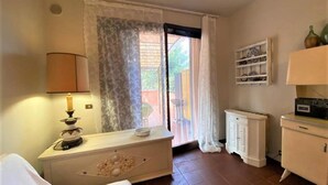 Une pièce comprenant un lit, une table de chevet avec une lampe, une commode, un placard et une étag ère avec des objets décoratifs.