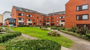 A multi-story brick building with a reception area, outdoor seating, and a well-maintained garden. - For Students Only Regents Court in Leicester (Leicester)