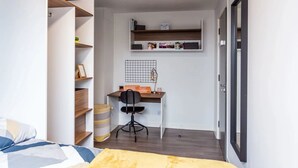 A compact bedroom with a bed, a desk, and shelving. - For Students Only Regents Court in Leicester (Leicester)