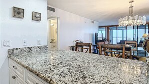 Una cocina con encimeras de granito, sillas de madera y una araña.