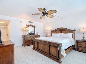 A bedroom with a wooden bed, a ceiling fan, a dresser, and a nightstand with a lamp. - Beachfront Getaway at Caper Beach Club #PH12 | Private Chiller/Heated Pool (Fort Myers Beach)