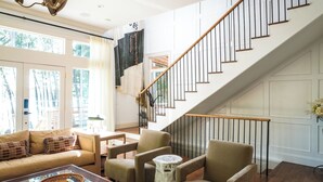 Un salon spacieux comprenant un canapé, des fauteuils, une table basse et un escalier.