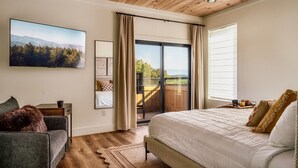 Een slaapkamer met een groot bed, een bank, een televisie en uitzicht op de omgeving.