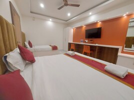 A hotel room with a large bed, a desk, a TV, and a ceiling fan.