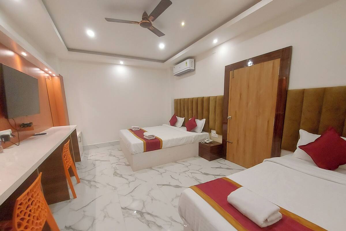 A hotel room with two beds, a desk, and a television.