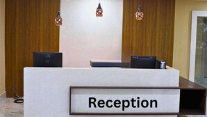 Ein Empfangsbereich mit Marmorplatte und einem Schild mit der Aufschrift 'Reception'. Über dem Empfangstresen hängen zwei Pendelleuchten, und dahinter befindet sich eine Wandpaneele aus Holz.