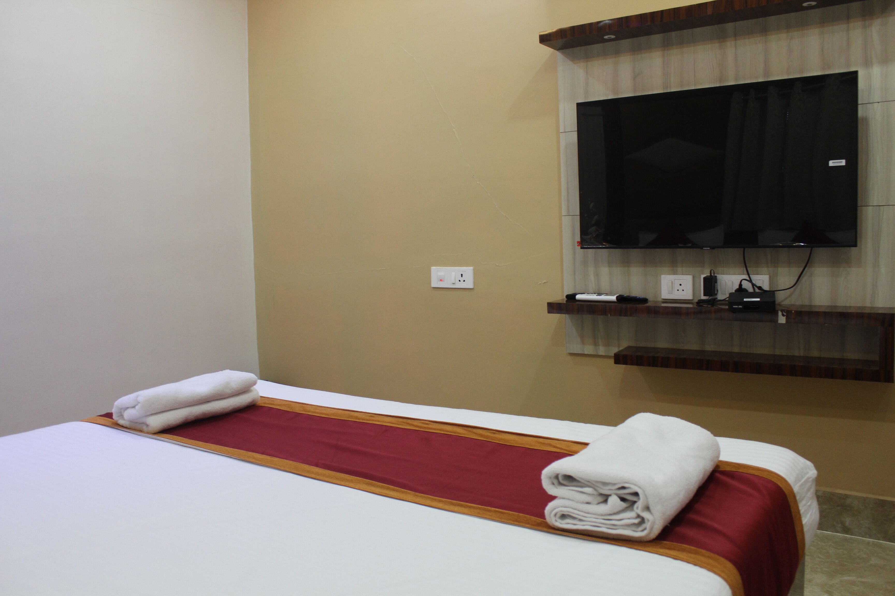 Une chambre d’hôtel équipée d’un lit, d’un téléviseur fixé au mur et d’une prise de courant.