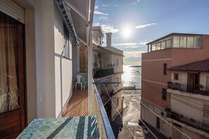 A balcony with a view of the sea, a table with a patterned tablecloth, and a chair. - BEAUTIFUL BEACHFRONT APARTMENT WITH PRIVATE PARKING JUST A FEW STEPS FROM TAORMINA (Giardini Naxos)