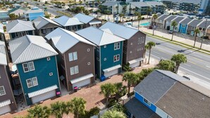 Zona residencial costera con casas modernas, una playa y edificios altos al fondo.