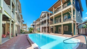 Una piscina con una marca de profundidad de 90 centímetros, rodeada de edificios de varios pisos con balcones y un sendero de ladrillo.