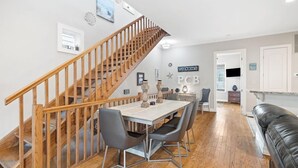 Un comedor con una escalera de madera, una mesa con sillas y vistas al área de la cocina.