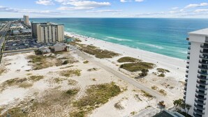 Vista costera con playa, estacionamiento y un edificio de gran altura.
