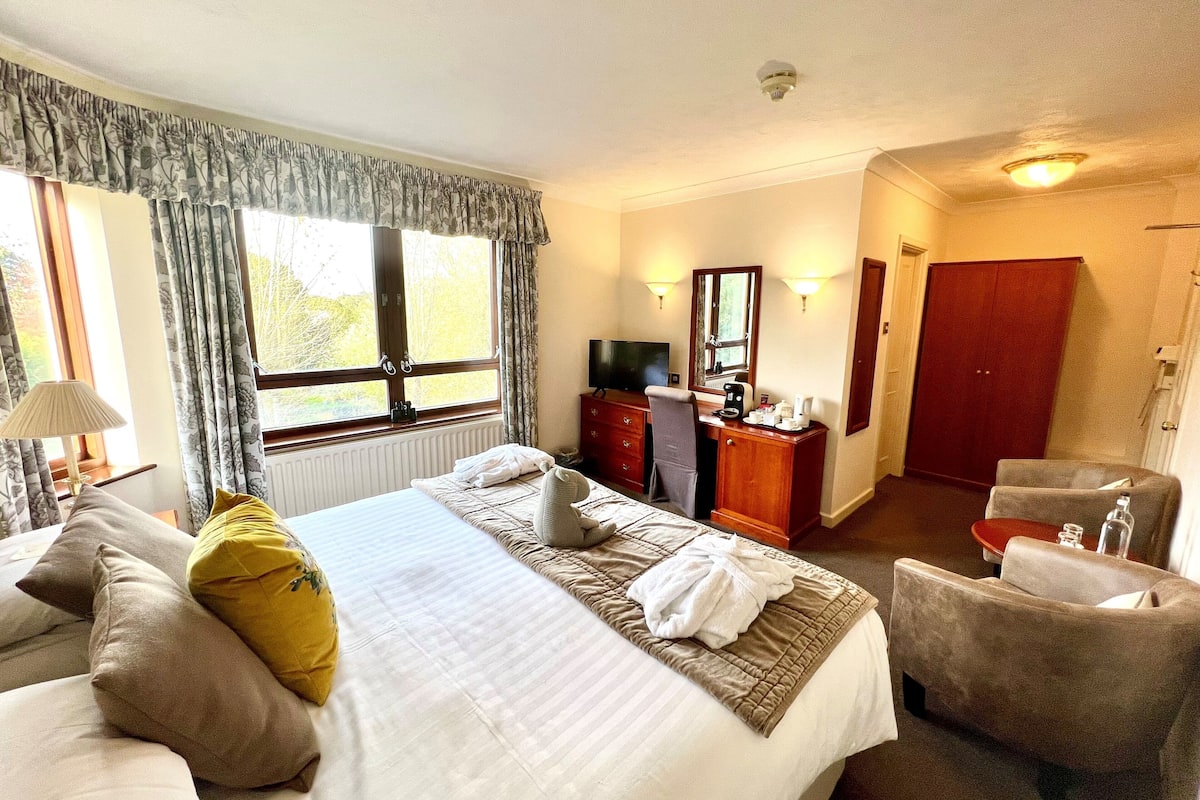 Une chambre d’hôtel avec un grand lit, un bureau avec un miroir, une télévision et une armoire.