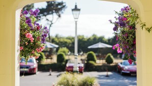 Une vue à travers une arche ornée de fleurs suspendues, avec un lampadaire en arrière-plan.