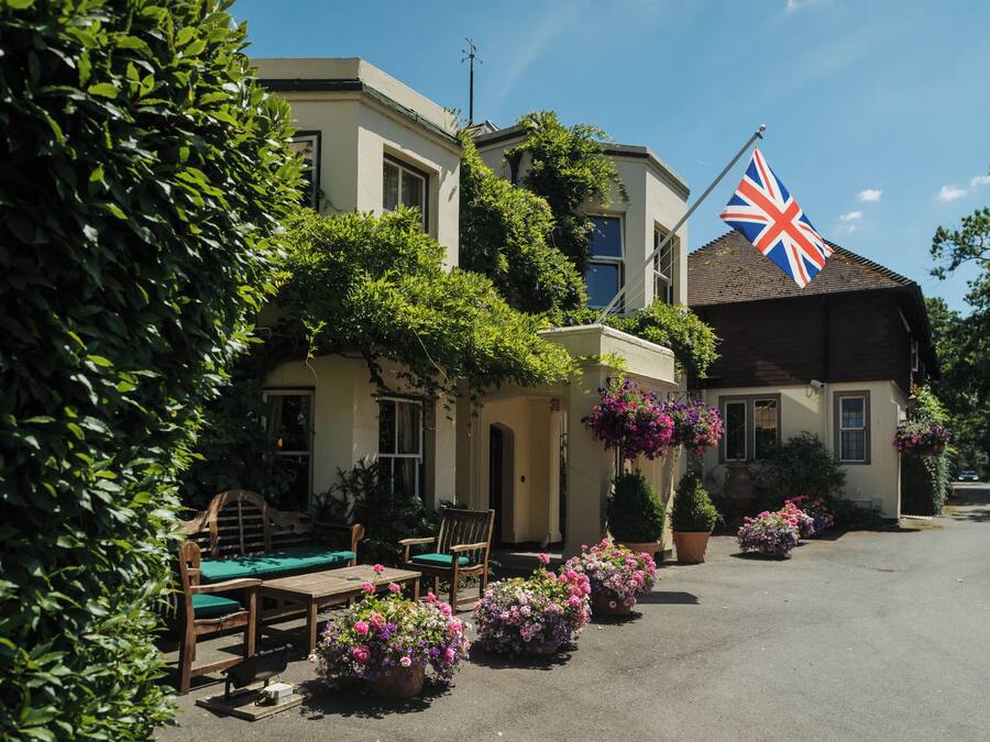 Un edificio con una bandera, mesas al aire libre y plantas en macetas.