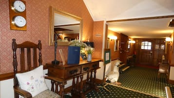A traditional interior with a wooden chair, a mirror, clocks, and a green patterned carpet.