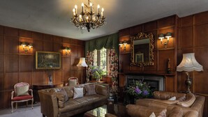 Une pièce de style traditionnel avec des boiseries, une cheminée, des canapés en cuir et un lustre.