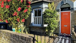 A two-story brick house with a red door, a small window, and a black and white checkered pathway leading to the entrance. - the crown loft (Kingston upon Thames)