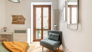 Une chambre à coucher avec un lit, un bureau, une chaise, une fenêtre et une porte.