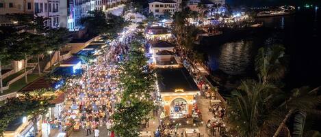 A bustling waterfront promenade with outdoor seating areas and a variety of shops and restaurants.