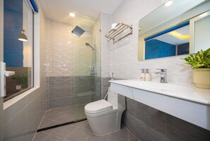 A modern bathroom with a glass-enclosed shower, a white toilet, and a vanity with a mirror and sink. - Tiamo Hotel (Phu Quoc)