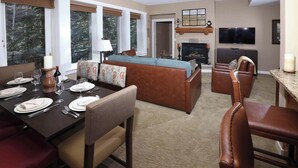 A modern living room with a fireplace, a television, and a dining area with a table set for four.
