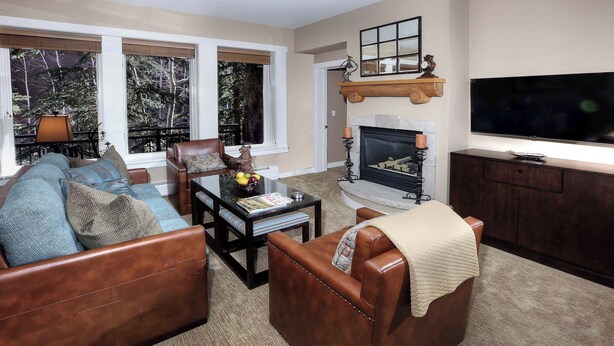 A living room with a brown leather sofa, a coffee table with magazines, a fireplace, and a television on a wooden cabinet.