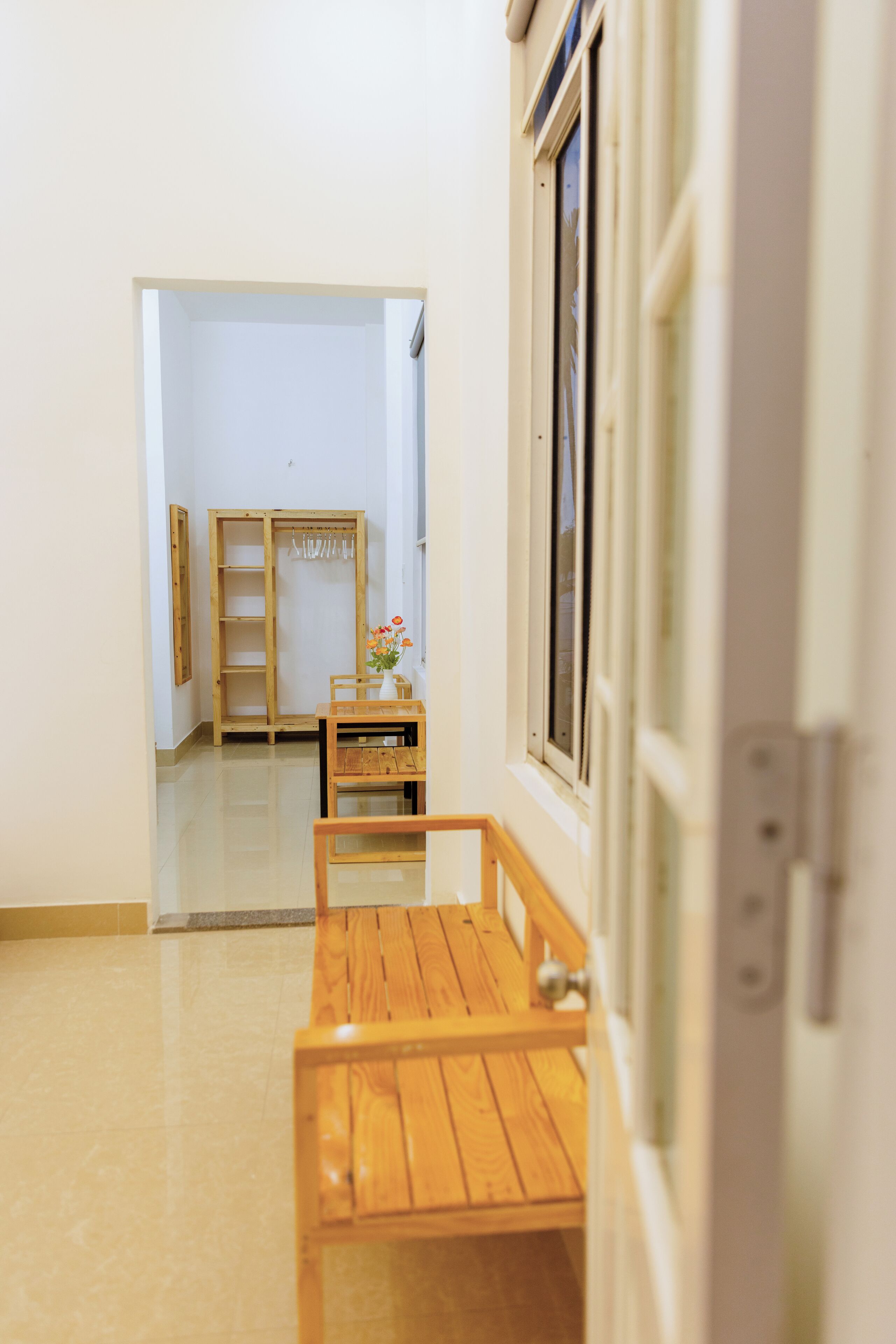 Un couloir avec un banc en bois, une armoire en bois et une fenêtre.
