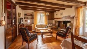 A cozy living room with wooden beams, a fireplace, and a sofa. - Le Clos du Prince, Country house with private pool and enclosed garden, ideal for families! (Saint-Vincent-Rive-d'Olt)