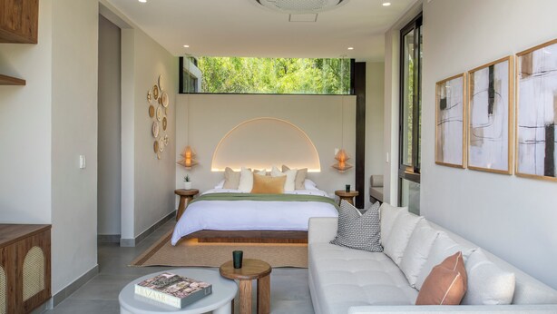 A modern bedroom with a large bed, bedside tables, a sofa, and a coffee table.